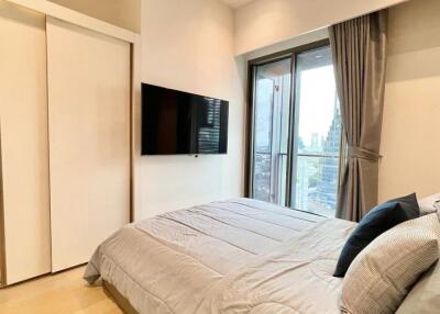 Modern bedroom with sliding closet doors, wall-mounted TV, and large window with city view