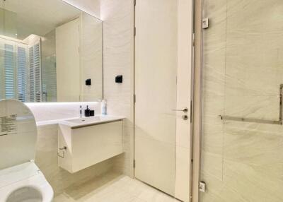 Modern bathroom with toilet, vanity unit, and large mirror
