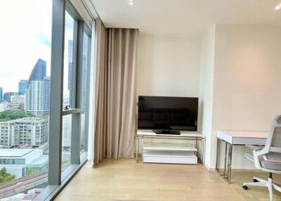 Modern living room with large window view, wall-mounted TV, and office desk