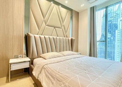 Modern master bedroom with a large bed, stylish headboard, and floor-to-ceiling windows with a city view