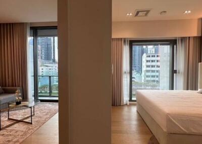 Living room and bedroom with large windows leading to a balcony in a modern apartment