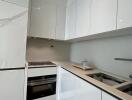 Modern kitchen with white cabinetry, built-in oven, electric cooktop, and sink