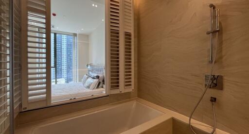 Modern bathroom with bathtub and open windows to a bedroom