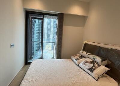 Small bedroom with a large bed and access to a balcony with city views
