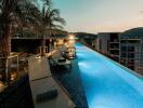 Rooftop infinity pool at sunset with lounge chairs and palm trees