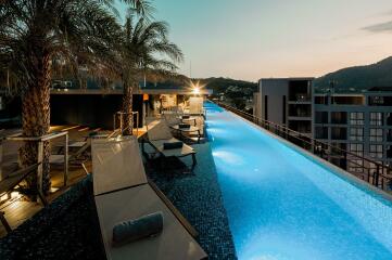 Rooftop pool with lounge chairs and city view at sunset