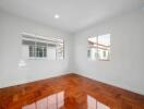 Empty bedroom with large windows and wooden floors