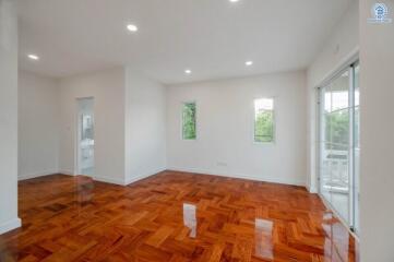 Spacious living room with glossy wooden flooring and large windows