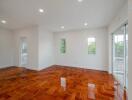 Spacious living room with glossy wooden flooring and large windows