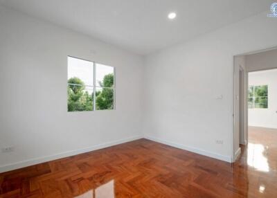 Empty bedroom with wooden flooring and window providing natural light