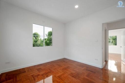 Empty bedroom with wooden flooring and window providing natural light