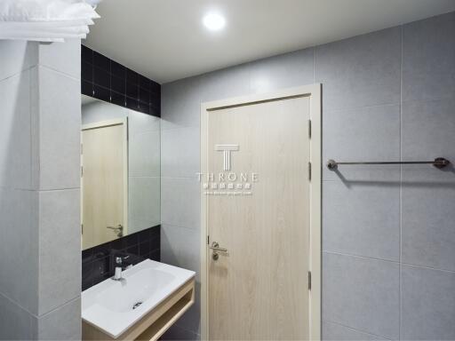 Modern bathroom with sink, mirror, and wooden door