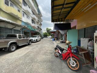 A street view with parked vehicles, buildings, and a motorcycle