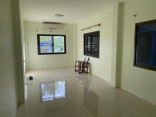 Spacious living room with large windows and tiled flooring