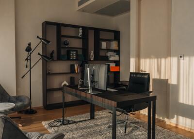 Modern home office with bookshelf, black desk, and leather chair