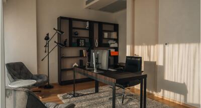 Modern home office with bookshelf, black desk, and leather chair