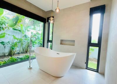modern bathroom with freestanding tub and large windows overlooking garden