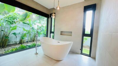 modern bathroom with freestanding tub and large windows overlooking garden