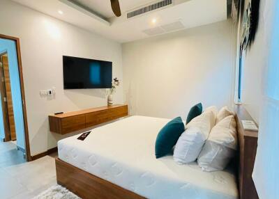 Modern bedroom with a large bed, TV, and wooden furniture