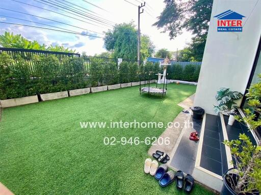 Well-maintained garden with artificial grass, seating area, and lush greenery