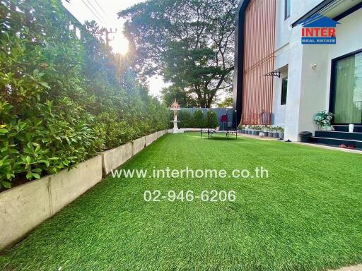 Outdoor lawn area with bushes and modern house