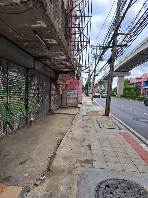 Street view showcasing storefronts with graffiti, sidewalks, and nearby road infrastructure