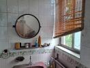 Bathroom with a mirror, sink, and window with blinds