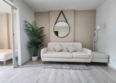 Living room with sofa, plant, mirror, and floor lamp