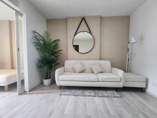 Living room with sofa, plant, mirror, and floor lamp