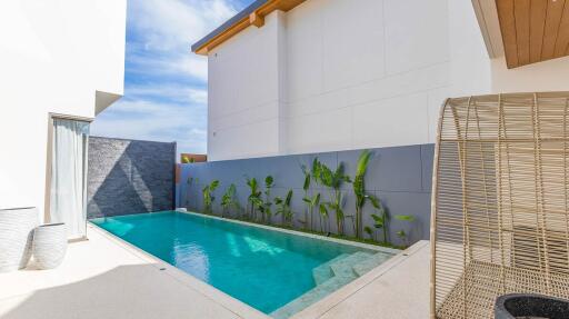 Modern outdoor pool area with plants and wicker furniture
