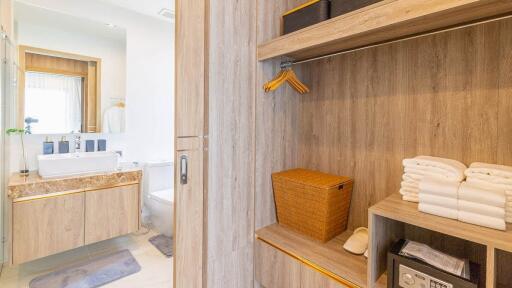 Modern bathroom with sink, mirror, toilet, and adjacent wooden closet