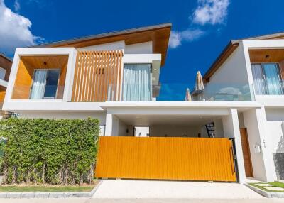 Modern two-story house exterior with a large wooden gate and lush greenery