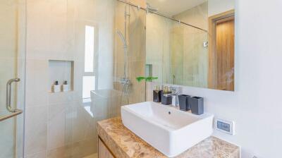 Modern bathroom with sink, glass shower, and amenities