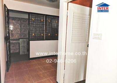 Photo of a room with tiled flooring, metal grill window and bathroom in the background