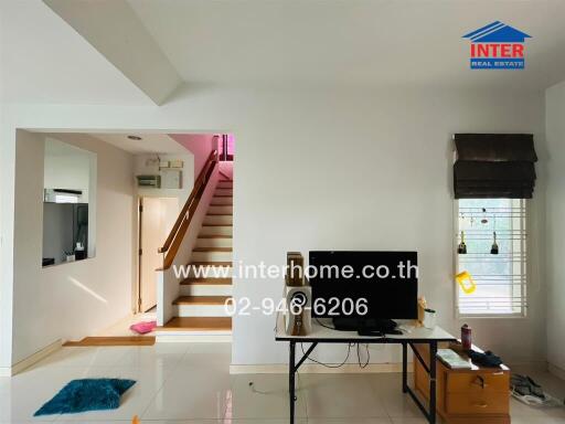 Spacious living room with staircase and TV setup