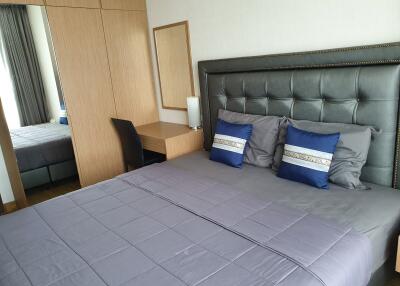 Modern bedroom with grey upholstered headboard, purple bedspread, and wood furniture