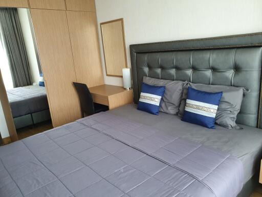 Modern bedroom with grey upholstered headboard, purple bedspread, and wood furniture