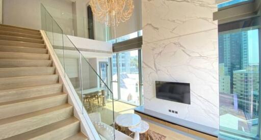 Modern living room with high ceilings, chandelier, and staircase