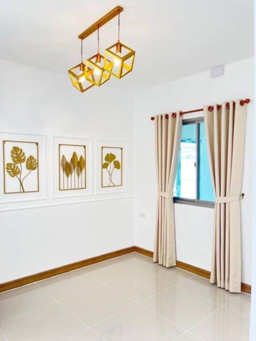 A small room with modern decor featuring framed artwork, curtain-covered window, and hanging pendant lights