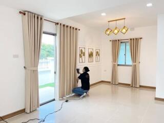 Modern living room with large windows, curtains, and a photographer taking pictures