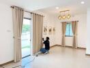 Modern living room with large windows, curtains, and a photographer taking pictures