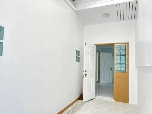 Plain white-walled room with open door leading to another room