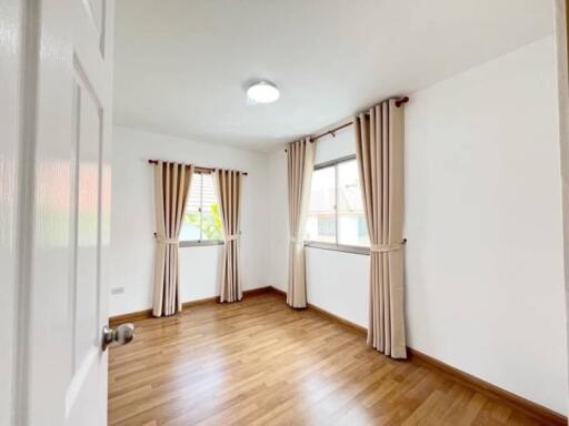 Bright bedroom with wooden floor and curtains