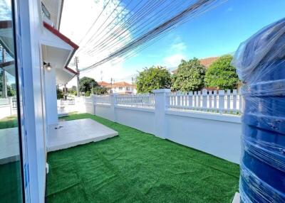 Backyard with green artificial turf and white picket fence