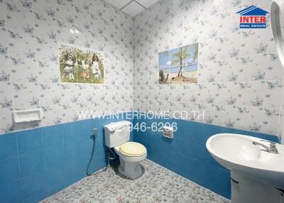 Bathroom with blue and white tile decor, featuring a toilet, sink, and wall art