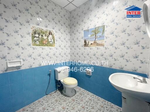 Bathroom with blue and white tile decor, featuring a toilet, sink, and wall art