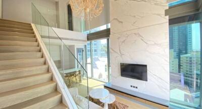 Modern living area with high ceilings, glass railings, and a chandelier