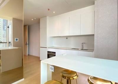 Modern kitchen area with white cabinets, wooden floors, and natural light from large windows