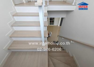 Modern staircase with wooden steps and white railing in a well-lit area