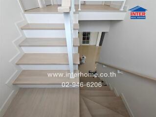 Modern staircase with wooden steps and white railing in a well-lit area